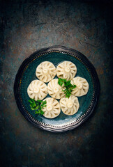 half-eaten Khinkali, a traditional Georgian dish, with spices and herbs, on a gray plate, top view, no people,