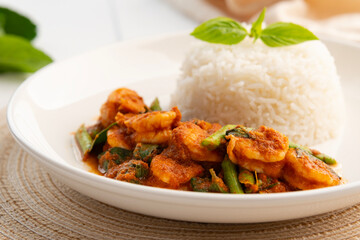 Close up Stir Fried Shrimp and yardlong bean with Red Curry Paste in white plate with cooked thai jasmine rice.