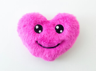 Pink fluffy heart toy smiling on a white background