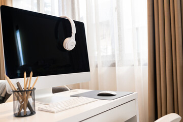 White headphones placed on a computer monitor after a break from an online meeting.