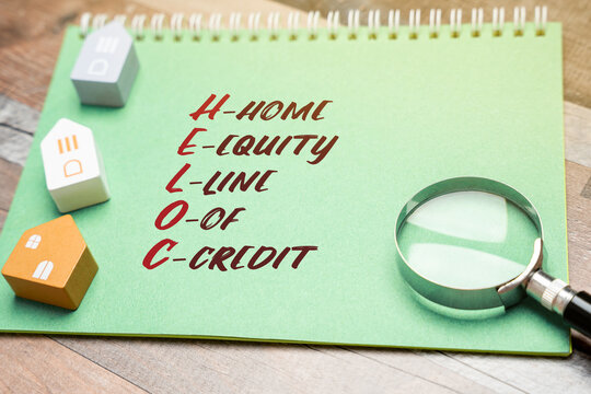 Heloc concept - Home equity line of credit. A line of credit extended to a homeowner that uses the borrowers home as collateral. Business and finance. Miniature houses, magnifying glass and notepad