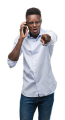 Young african american man using smartphone pointing with finger to the camera and to you, hand sign, positive and confident gesture from the front