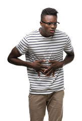 Fototapeta premium Young african american man wearing glasses and navy t-shirt with hand on stomach because indigestion, painful illness feeling unwell. Ache concept.