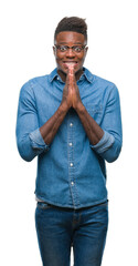 Young african american man over isolated background praying with hands together asking for forgiveness smiling confident.