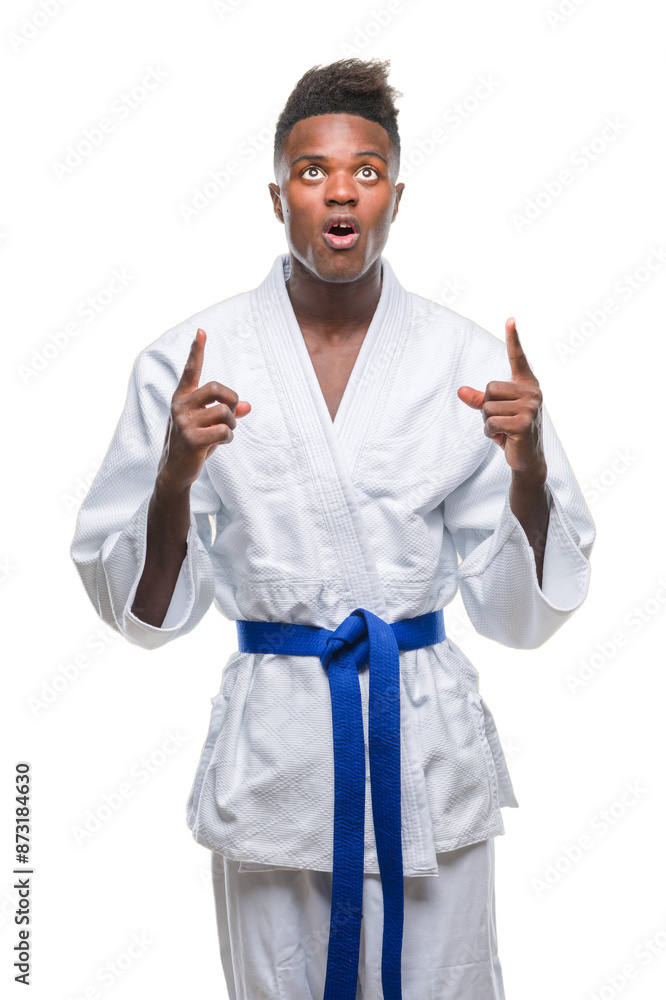 Canvas Prints Young african american man over isolated background wearing kimono amazed and surprised looking up and pointing with fingers and raised arms.