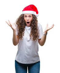 Young brunette girl wearing christmas hat over isolated background celebrating crazy and amazed for success with arms raised and open eyes screaming excited. Winner concept