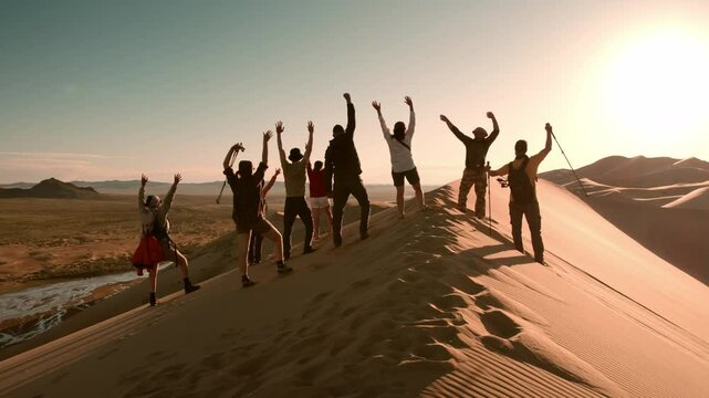 Big group of diverse happy tourists are standing on sunset sand dune and having fun with open arms against sunset sky and great view