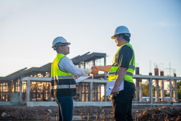 Two Architect man holding hand after finish discussing about the building plan at the construction site