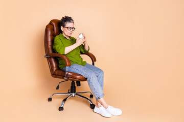 Full body photo of attractive retired woman sit armchair stress crumpled paper dressed green clothes isolated on beige color background