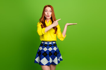 Photo portrait of lovely young lady amazed hold point empty space dressed stylish yellow garment isolated on green color background