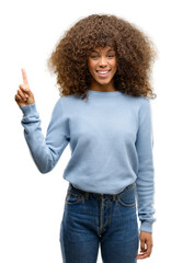 African american woman wearing a sweater showing and pointing up with finger number one while smiling confident and happy.