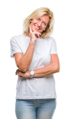 Middle age blonde woman over isolated background looking confident at the camera with smile with crossed arms and hand raised on chin. Thinking positive.