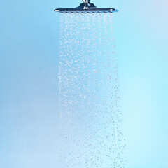 Water, running and shower head in studio, skincare and morning routine in bathroom for cleaning. Hygiene, grooming and flow on blue background, body wellness and fresh for maintenance in beauty spa