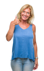 Middle age blonde woman over isolated background doing happy thumbs up gesture with hand. Approving expression looking at the camera with showing success.