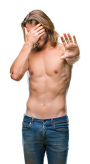 Fototapeta premium Young handsome shirtless man with long hair showing sexy body over isolated background covering eyes with hands and doing stop gesture with sad and fear expression. Embarrassed and negative concept.