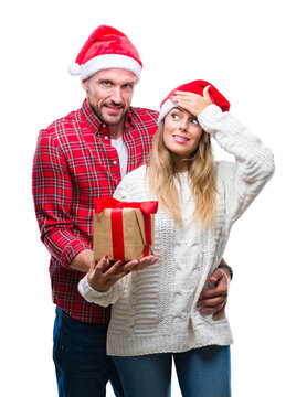 Young couple in love wearing christmas hat and holding present over isolated background stressed with hand on head, shocked with shame and surprise face, angry and frustrated. Fear and upset