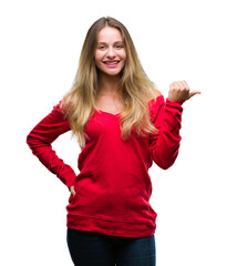 Young beautiful blonde woman wearing red sweater over isolated background smiling with happy face looking and pointing to the side with thumb up.