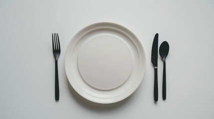 Plate with utensils on white background from above