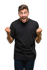 Naklejka premium Young handsome man over isolated background celebrating surprised and amazed for success with arms raised and open eyes. Winner concept.