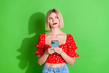 Photo of minded lovely cute woman wear red stylish clothes look poster empty space isolated on green color background