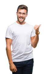 Naklejka premium Young handsome man wearing glasses over isolated background smiling with happy face looking and pointing to the side with thumb up.