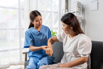 A woman in a blue scrubs is helping another woman with her arm