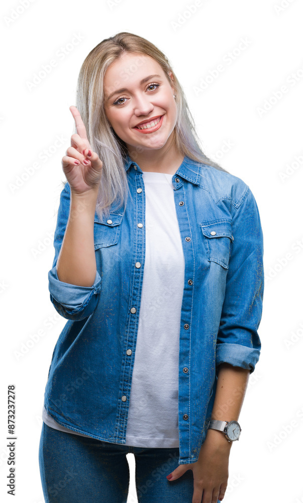 Poster young blonde woman over isolated background showing and pointing up with finger number one while smi