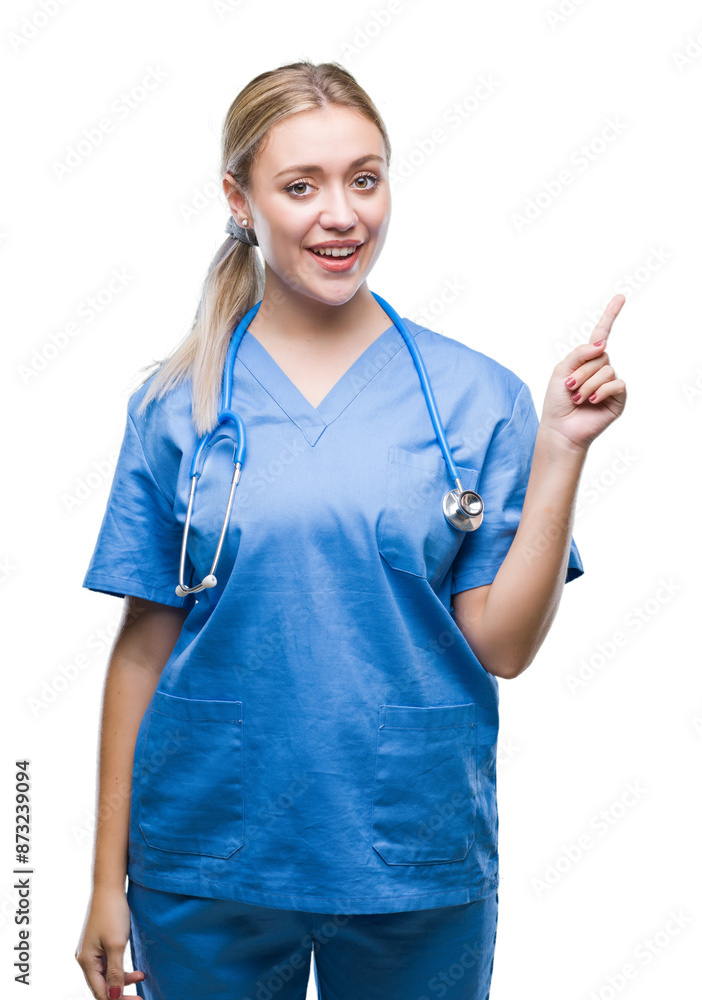 Canvas Prints Young blonde surgeon doctor woman over isolated background with a big smile on face, pointing with hand and finger to the side looking at the camera.