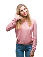 Fototapeta premium Young beautiful blonde woman wearing pink winter sweater over isolated background smiling doing phone gesture with hand and fingers like talking on the telephone. Communicating concepts.