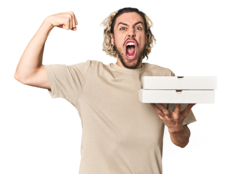 Young man holds pizza boxes for delivery raising fist after a victory, winner concept.