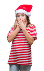 Young beautiful girl wearing christmas hat over isolated background shocked covering mouth with hands for mistake. Secret concept.