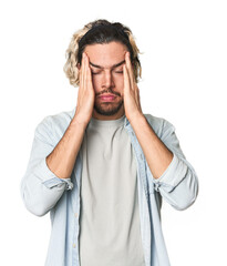 Naklejka premium Young Caucasian man in studio setting touching temples and having headache.