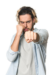 Young Caucasian man in studio setting throwing a punch, anger, fighting due to an argument, boxing.