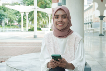 Fototapeta premium A smilling woman sitting using cell phone