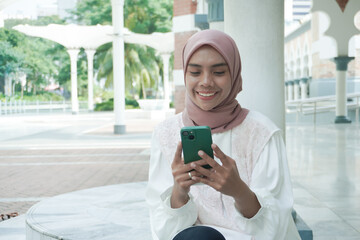Fototapeta premium A smilling woman sitting using cell phone