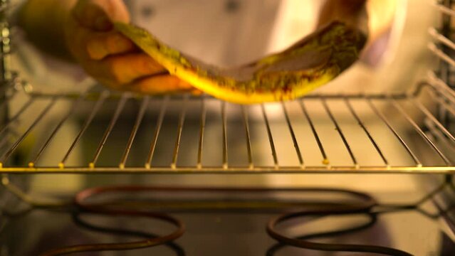 A chef puts a cooked pizza in the oven to bake.

