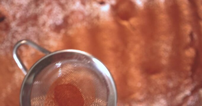  A cook sifts cinnamon powder onto the finished pie close-up view from above.
