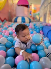 Fototapeta premium Asian baby boy playing ball bath in playground area.