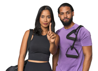 Young Latino couple ready for gym training showing number one with finger.