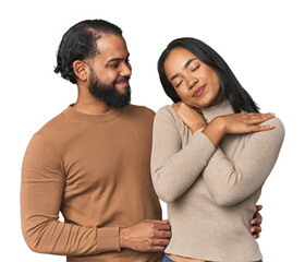 Young Latino couple in studio hugs, smiling carefree and happy.