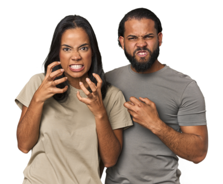 Young Latino couple in studio upset screaming with tense hands.