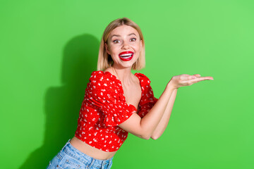 Photo of cheerful glad lovely cute woman wear red trendy clothes hold brand empty space isolated on green color background