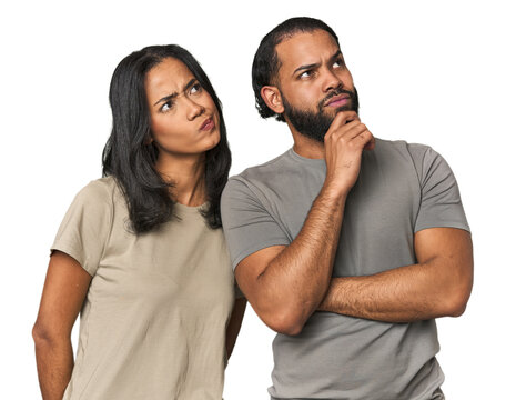 Young Latino couple in studio thinking and looking up, being reflective, contemplating, having a fantasy.