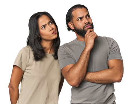 Young Latino couple in studio thinking and looking up, being reflective, contemplating, having a fantasy.