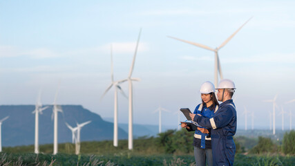Two engineers working and holding the report at wind turbine farm Power Generator Station on...