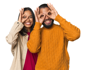 Young Latino couple in studio showing okay sign over eyes
