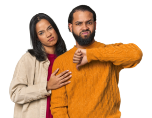 Young Latino couple in studio showing thumb down, disappointment concept.