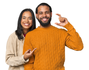 Young Latino couple in studio holding something little with forefingers, smiling and confident.