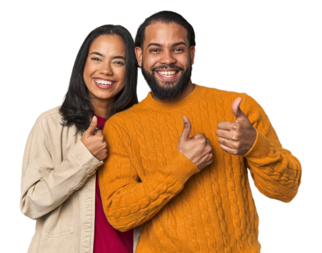 Young Latino couple in studio raising both thumbs up, smiling and confident.