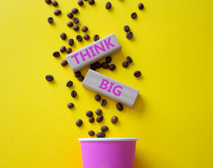 Think big symbol. Wooden blocks with words Think big. Beautiful yellow background with coffee cup. Business and Think big concept. Copy space.